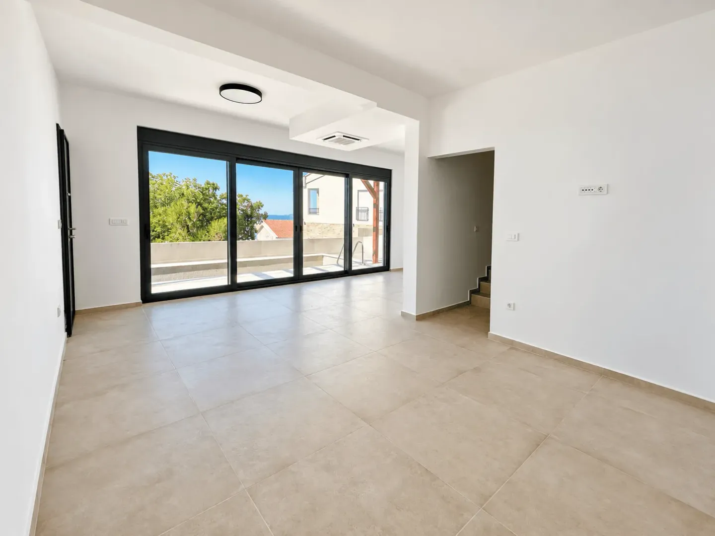 Empty living room with large glass openings and a view of the terrace.