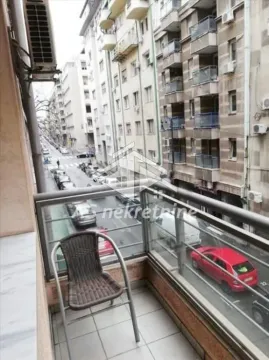Small balcony with a chair and a view of the street and buildings. - image 10