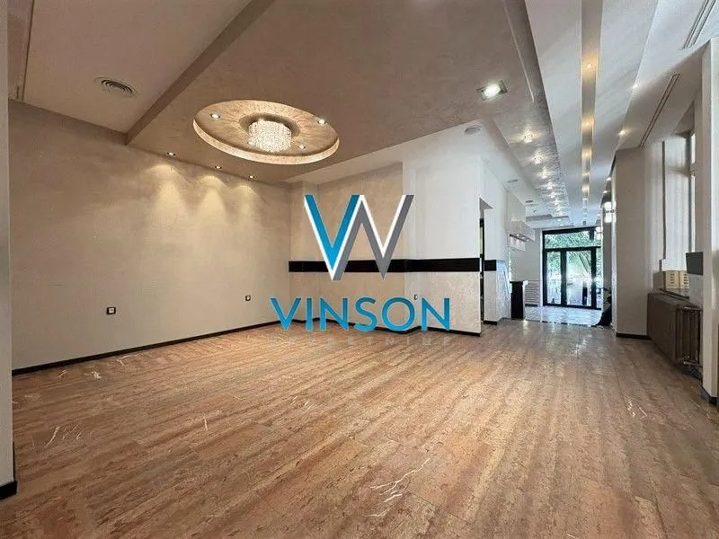 Spacious empty room with a drop ceiling and lighting.