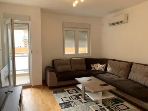 A bright living room with a corner sofa, a coffee table, and balcony access. - image 8
