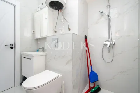 Small bathroom lined with marble tiles featuring a shower, sink, and toilet. - image 5