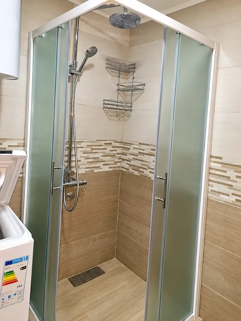 Modern bathroom with a shower cabin and ceramic tiles.