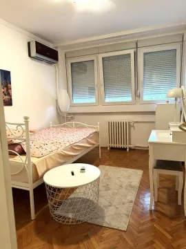 Furnished bedroom with a bed, desk, and windows. - image 10
