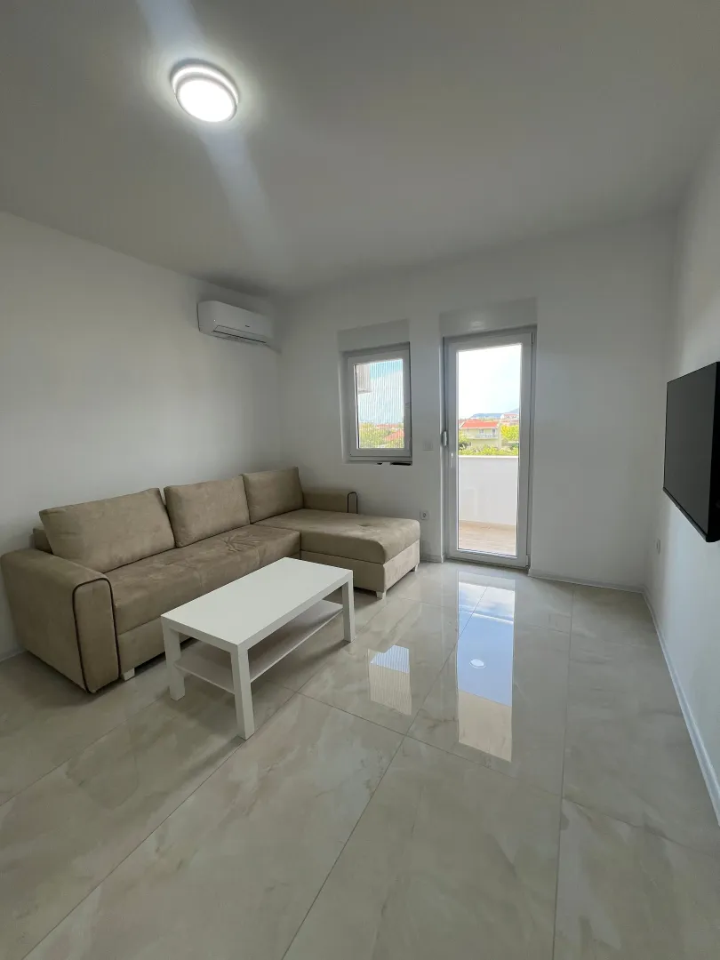 Bright living room with a sectional sofa, white coffee table, and access to the terrace.