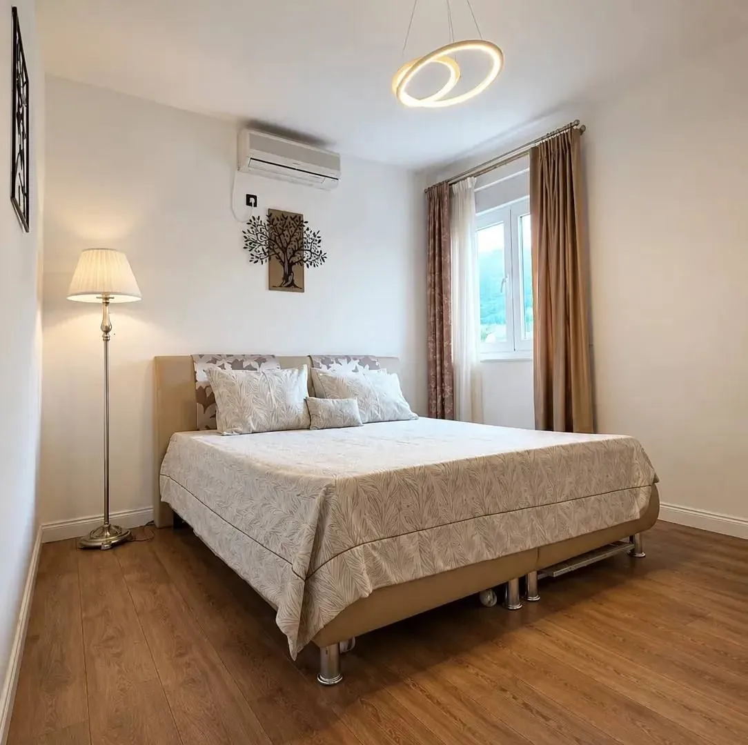 Furnished bedroom with a double bed and wooden flooring.