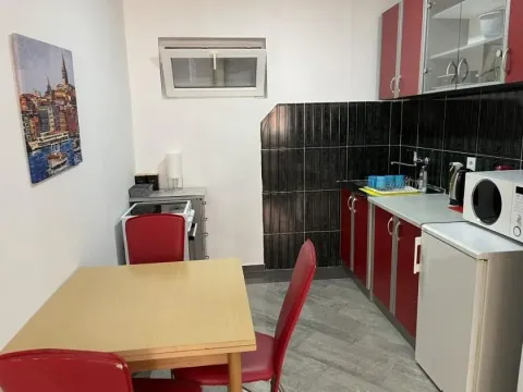 Smaller kitchen with a dining table and red cabinets. - image 3
