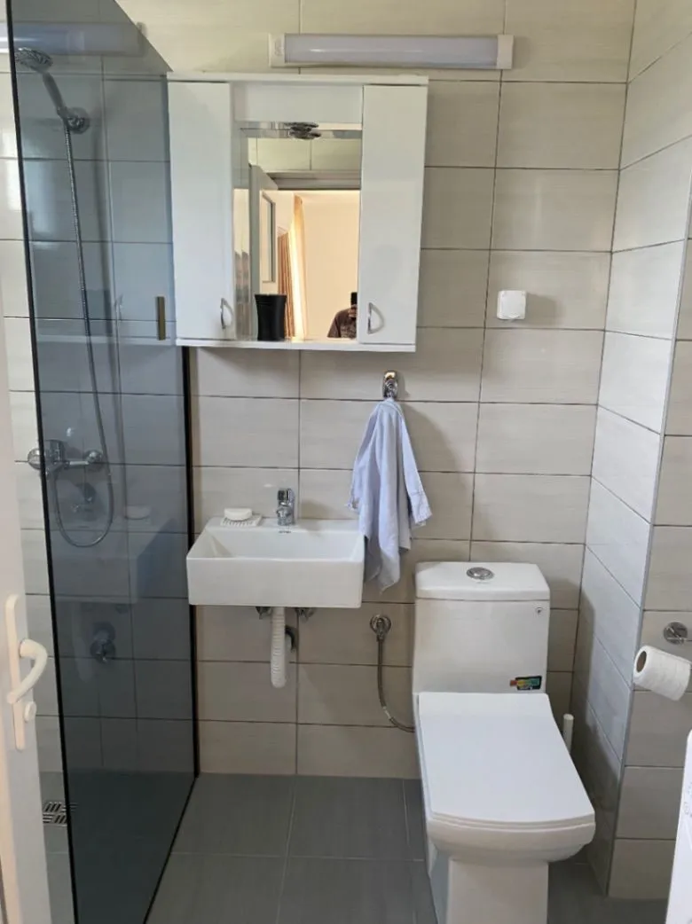 Manje opremljeno kupatilo sa tuš kabinom, umivaonikom i wc šoljom.