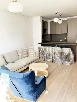 Living room with a sofa and dining area in the background. - image 17