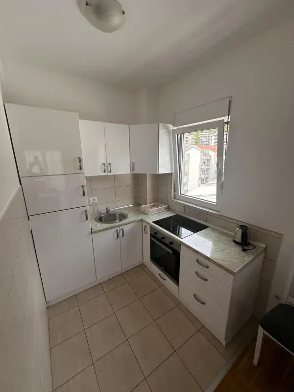 Small white kitchen with a built-in oven, hob, and refrigerator.