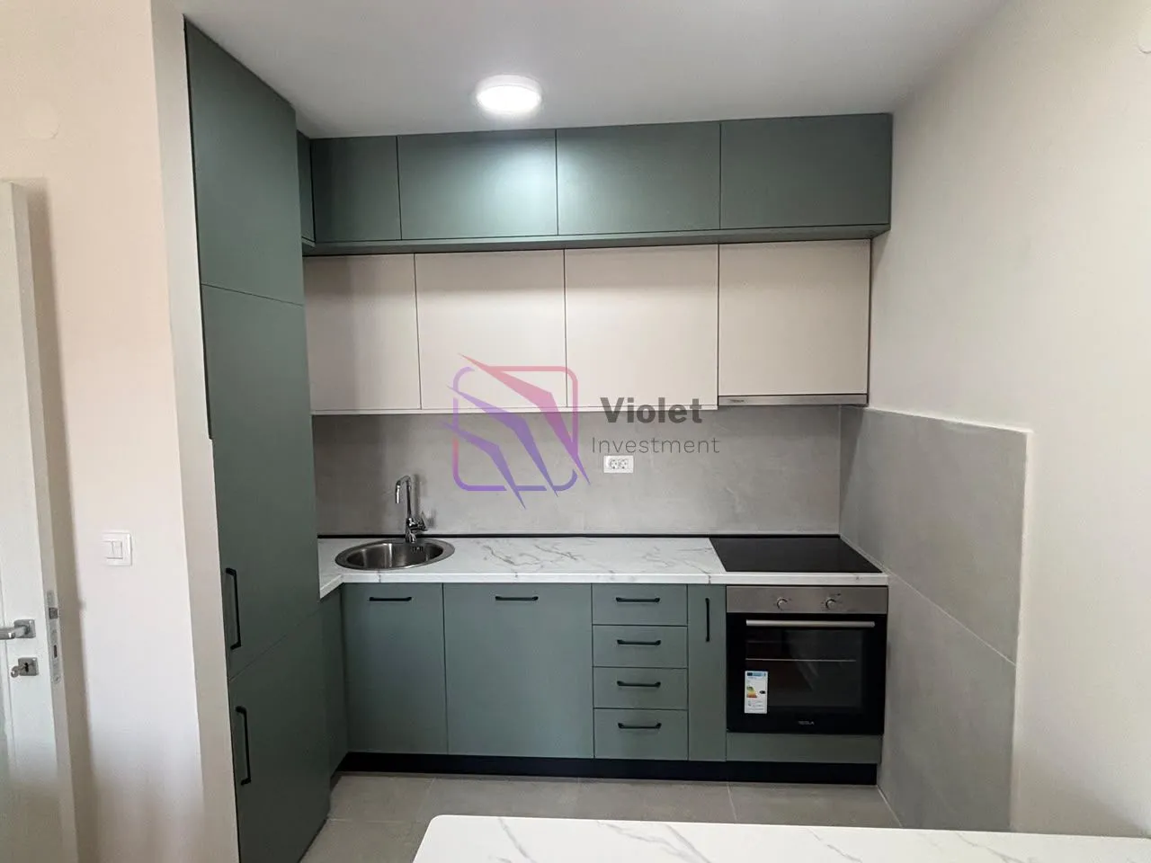 Modern kitchen with green and white cabinets and built-in appliances.