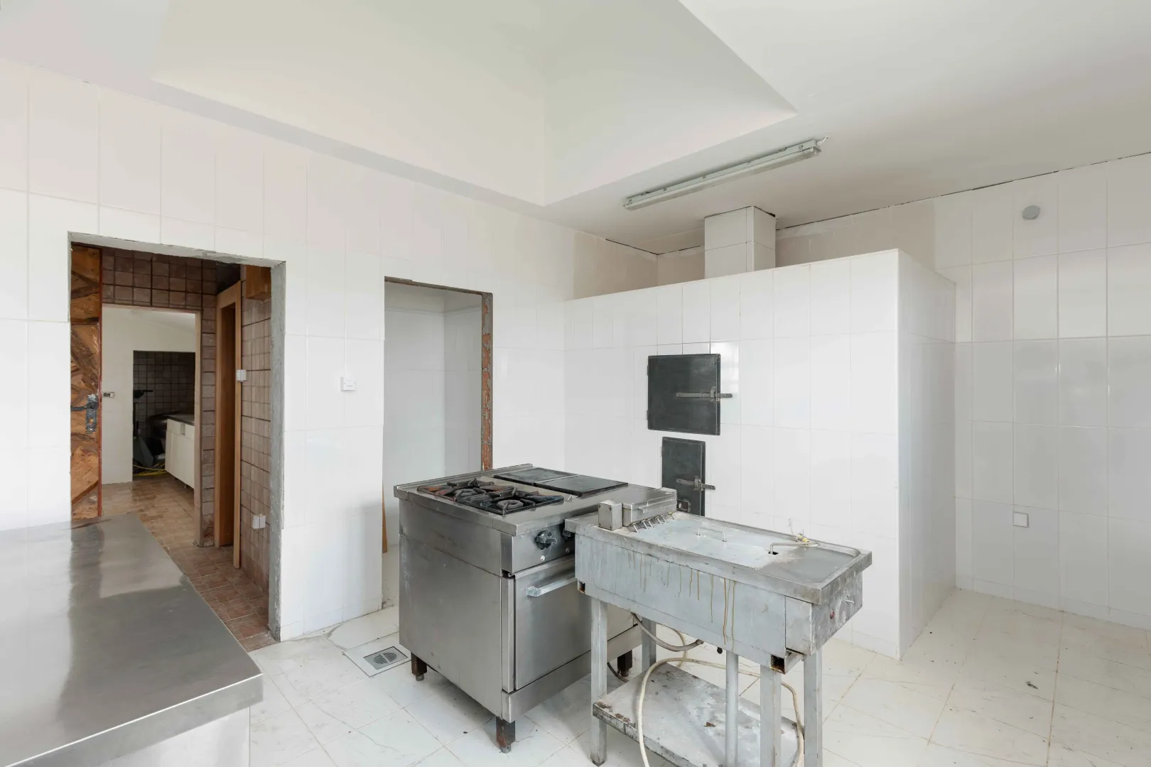 Empty commercial kitchen with ceramic wall tiles.