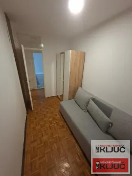 Manja spavaća soba sa sivim krevetom i ormarom. - image 3
