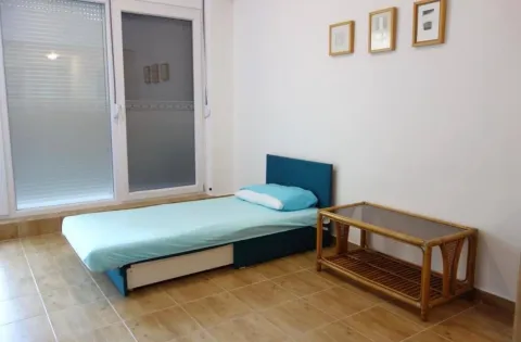 Namještena spavaća soba sa krevetom i malim stočićem. - image 3