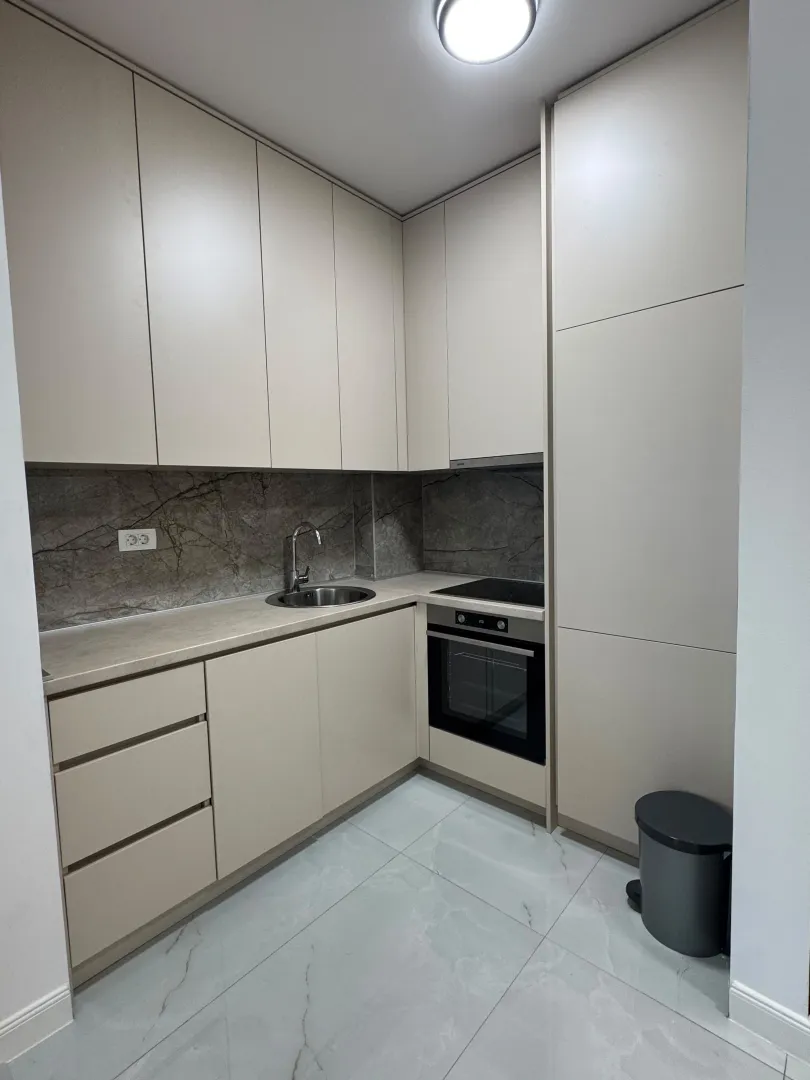 Modern kitchen with beige cabinets and a built-in oven.