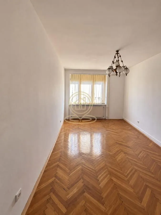 Empty room with parquet flooring and a window.