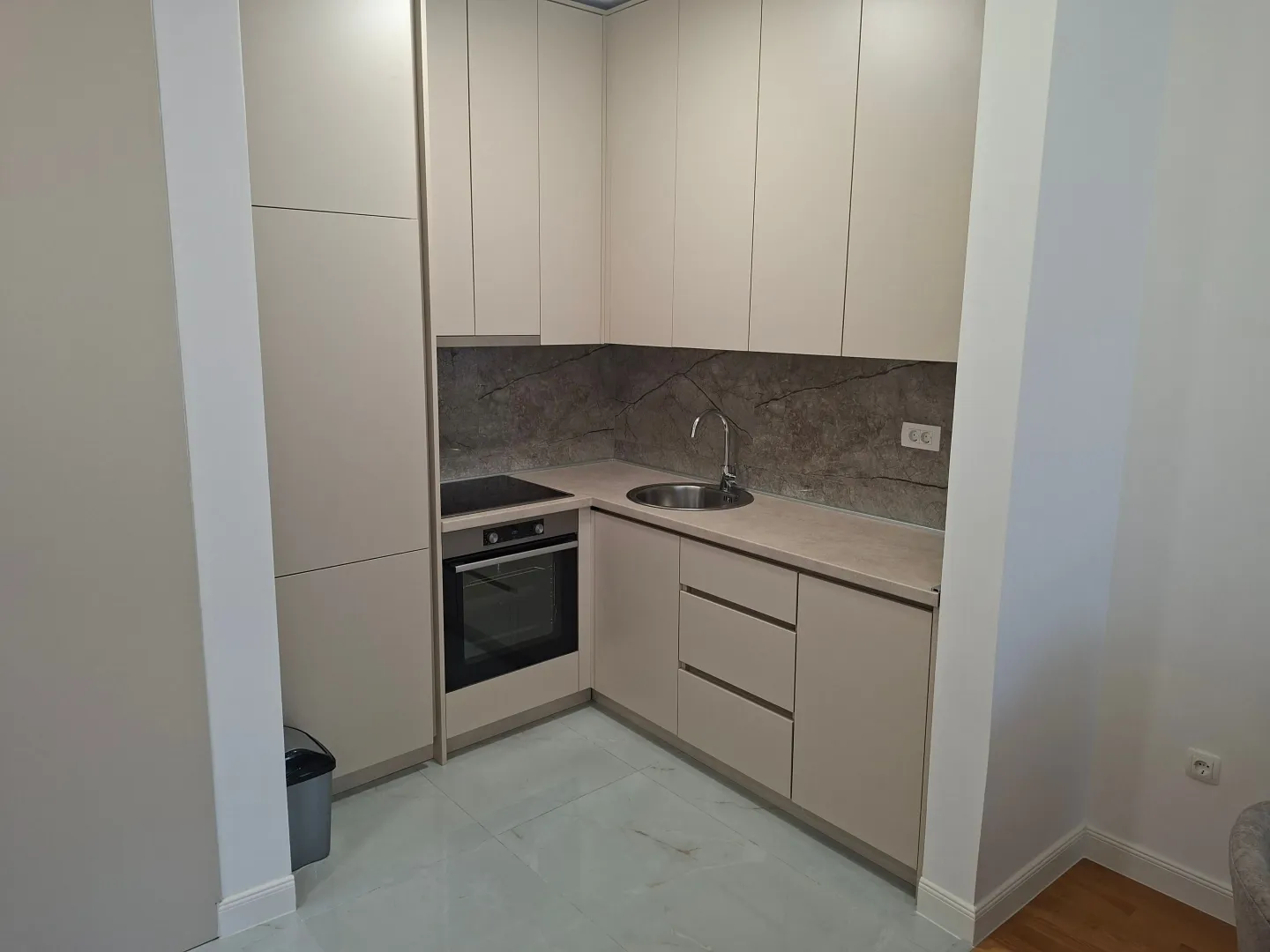 Modern kitchen in beige tones with built-in oven and cabinetry.