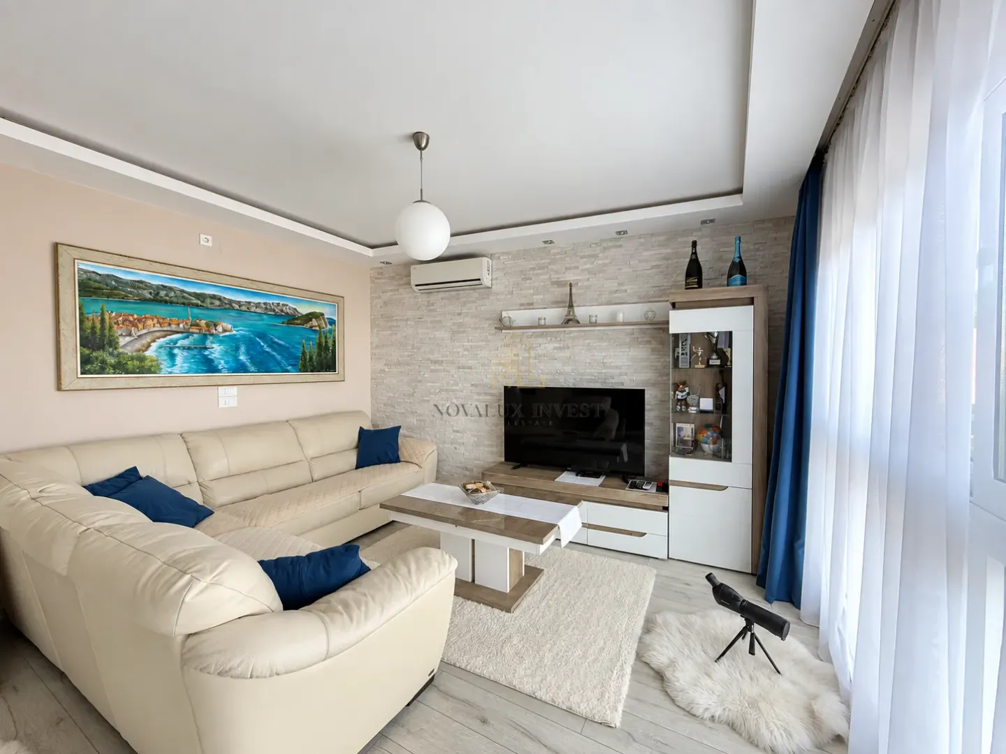 Living room with a sectional sofa, TV unit, and a large painting on the wall.