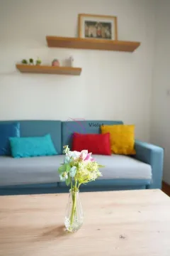 Living room with a blue sofa and a wooden coffee table with a vase of flowers. - image 3