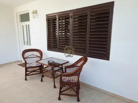 Covered terrace with wicker seating set and brown windows with shutters. - image 15