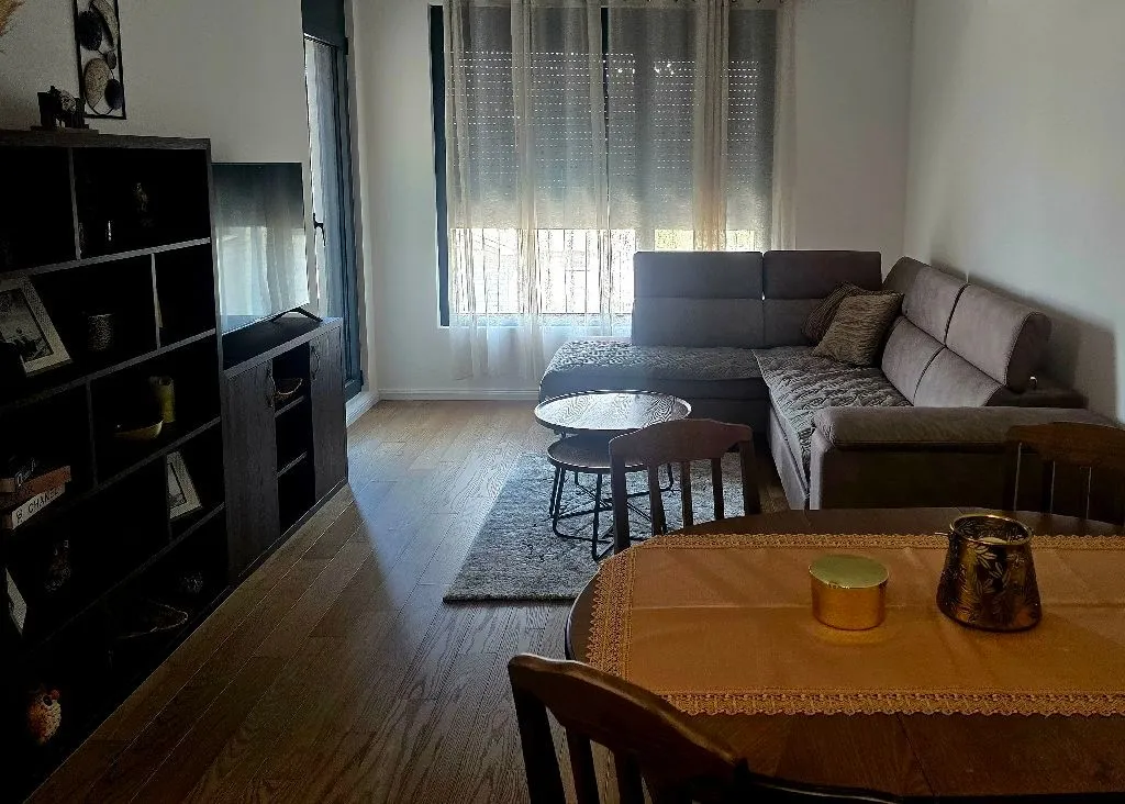 Living room with sofa, TV unit, and dining table.