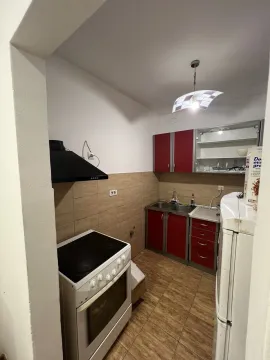 Jednostavna kuhinja sa crvenim elementima, šporetom i frižiderom. - image 7