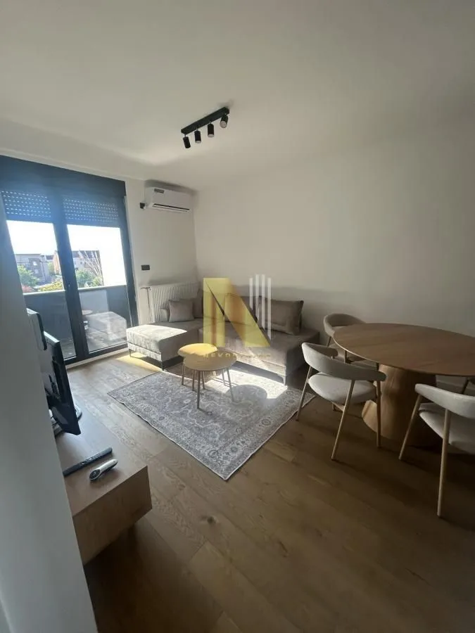 Dnevna soba sa garniturom, trpezarijskim stolom i izlazom na terasu.