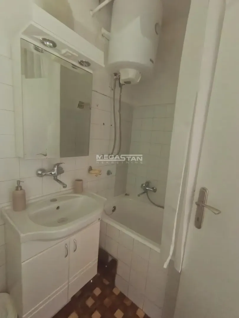 Smaller bathroom with a bathtub, washbasin, and mirror.