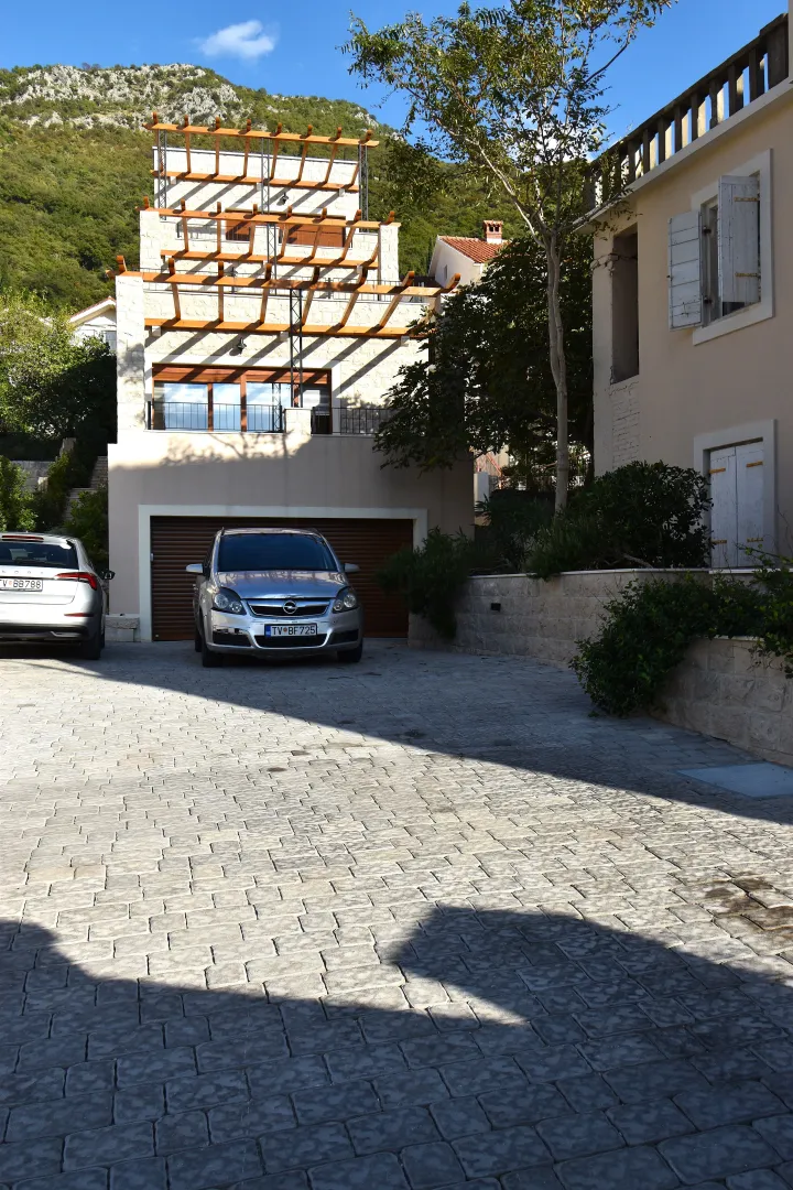 Dvorište sa popločanim parkingom ispred kuće.