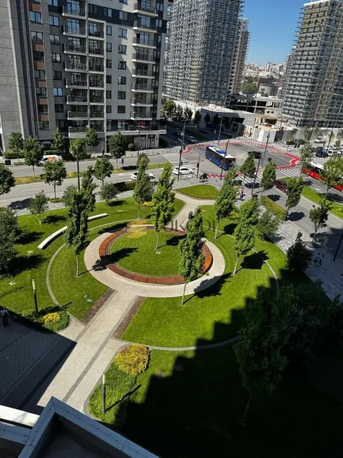 Pogled sa prozora na uređeni park i gradsku ulicu.