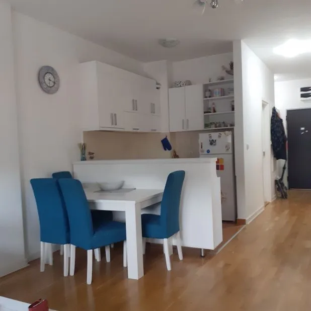 Small kitchen with white cabinets and a dining table with blue chairs.