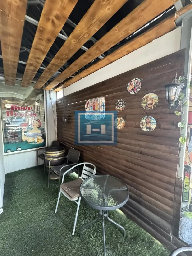Covered terrace with wooden wall paneling and garden furniture.