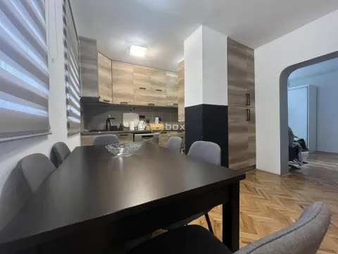 Dining area with a dark table and chairs, connected to the kitchen in the background. - image 5