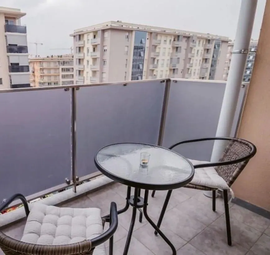 Furnished balcony with a table and chairs and a view of buildings.