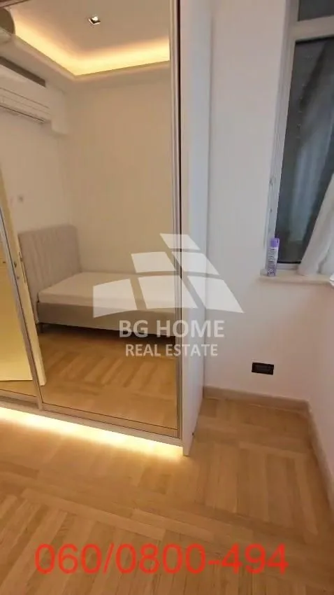 Small bedroom with a bed and a large built-in wardrobe with a mirror.
