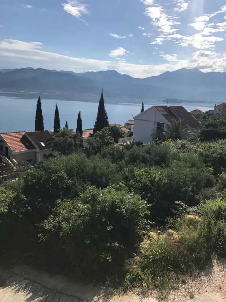 Pogled na more i planine sa okolnim kućama i zelenilom.