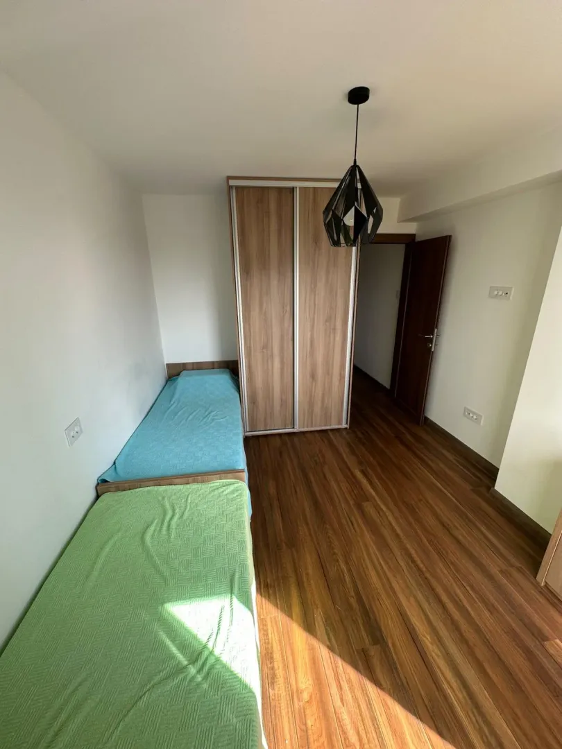 Spavaća soba sa dva kreveta i drvenim ormanom.
