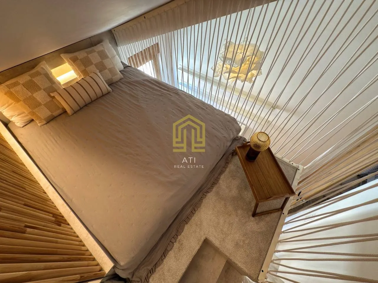 Bed with pillows and a wooden side table in an upstairs bedroom.