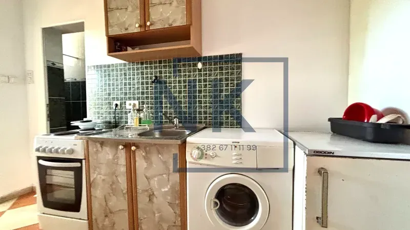 Manja kuhinja sa šporetom, sudoperom, veš mašinom i zidnim pločicama.