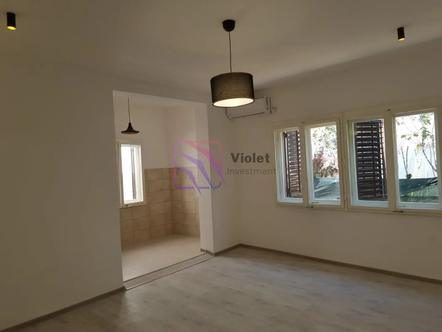 Empty living room with a view of the windows and an entrance to the kitchen.