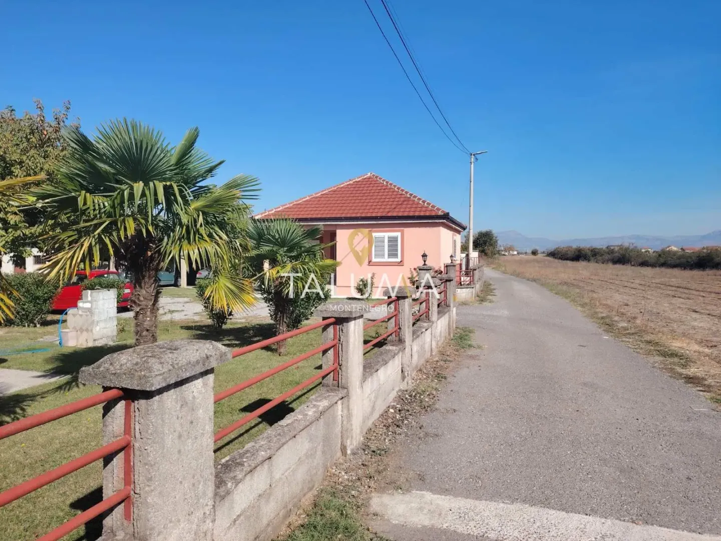 View of the exterior of the house with a yard and a fence by the road.