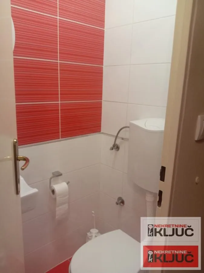 Manje kupatilo sa belim i crvenim zidnim pločicama i sanitarijama.