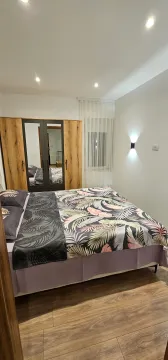 Uređena spavaća soba sa bračnim krevetom i drvenim ormarom sa ogledalom. - image 6