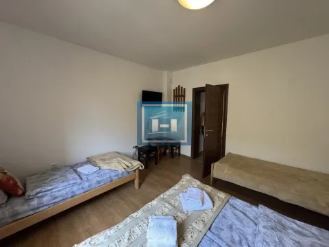 Bedroom with three beds, a television, and a wooden floor. - image 13