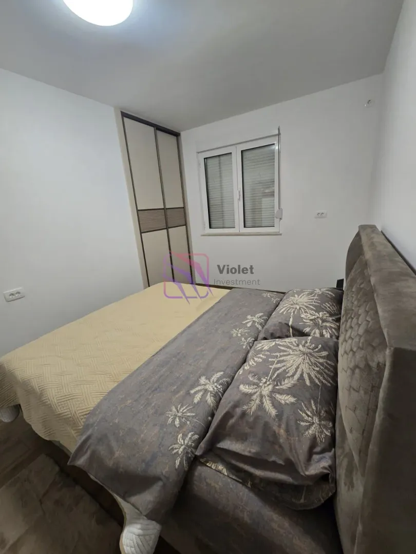 Namještena spavaća soba sa bračnim krevetom i ugradnim ormarom.