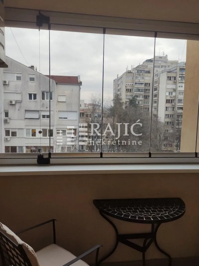Glazed balcony with a view of city buildings.