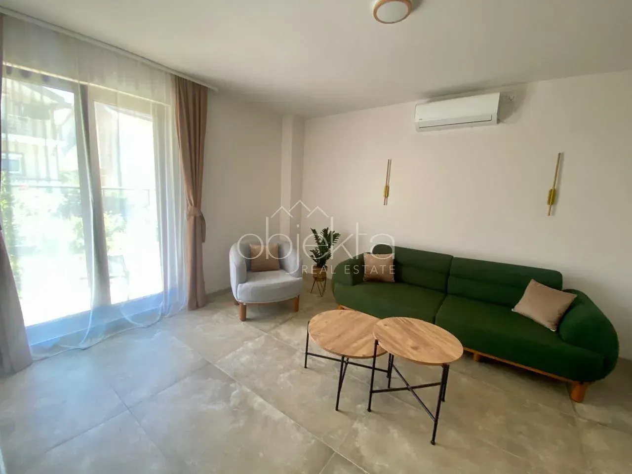 Living room with a green sofa, an armchair, and two small coffee tables.