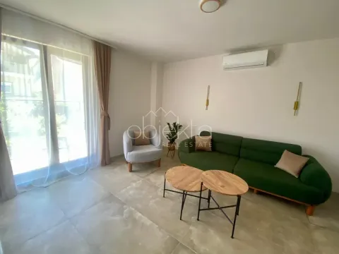 Living room with a green sofa, an armchair, and two small coffee tables. - image 8