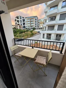 Manji namješten balkon sa stolom i dvije stolice i pogledom na okolne zgrade. - image 7
