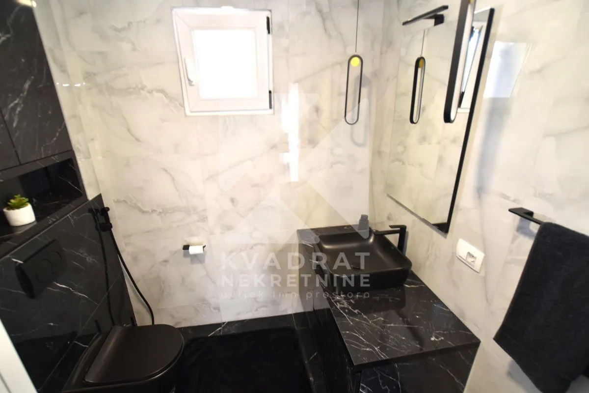 Modernly equipped bathroom with black sanitary ware and marble tiles.