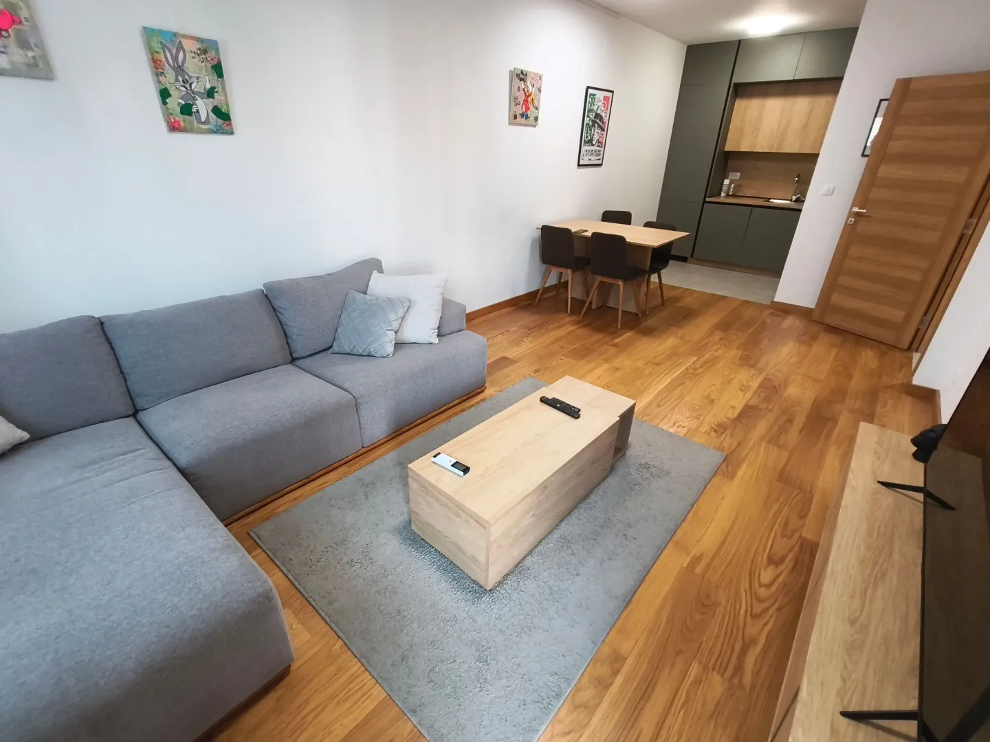 Dnevni boravak sa garniturom, stočićem i trpezarijom u pozadini.